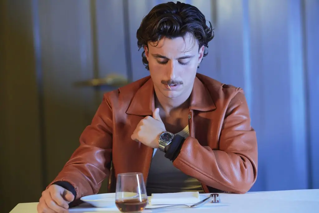 A man in a leather jacket checks his Komposition Black at the table