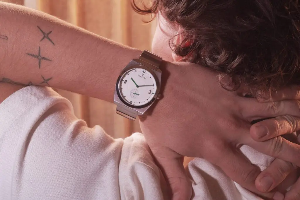 A Komposition Cream on a tattooed wrist, a hand held to the neck