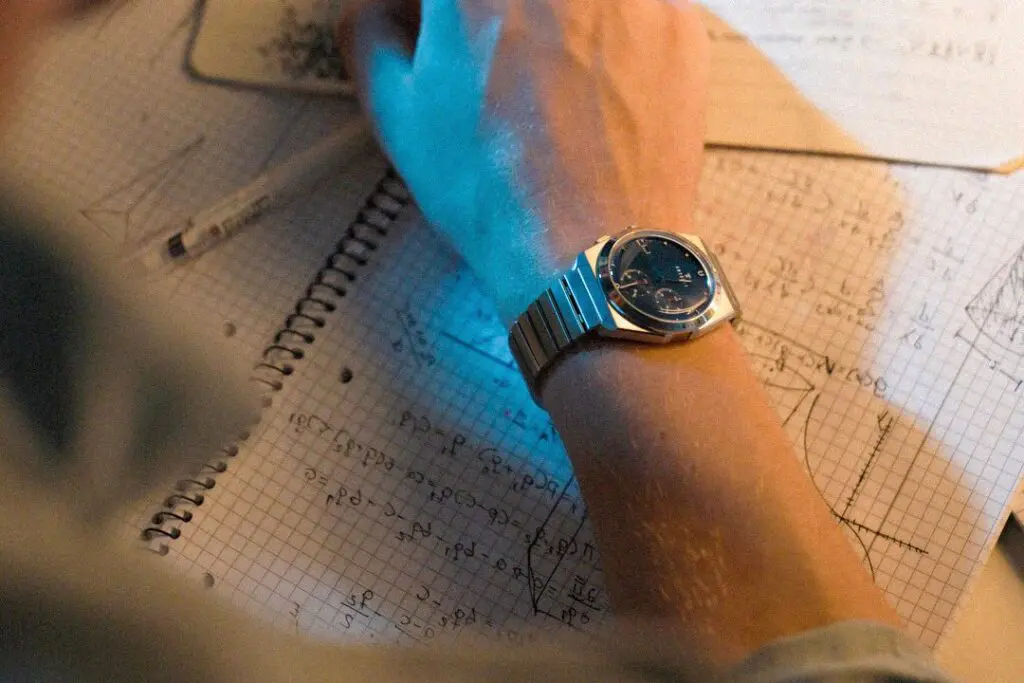 A hand over a notebook of sketches, a Komposition Chronograph Cool Navy on the wrist